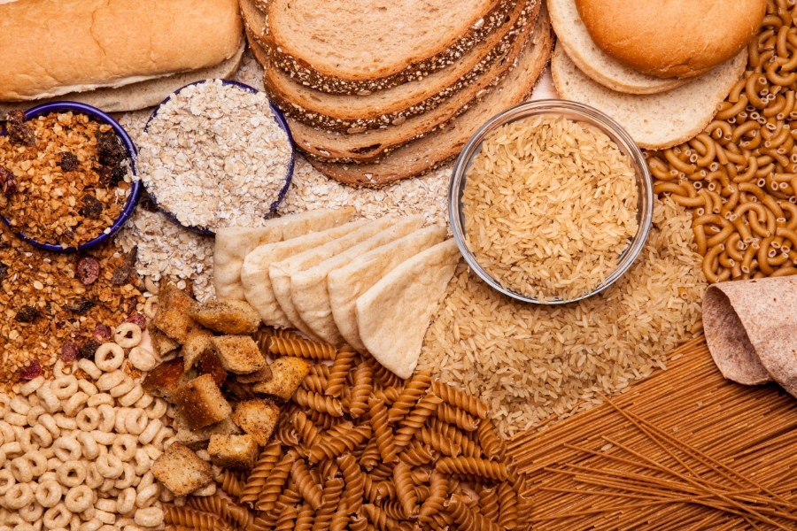 Variety of foods including oatmeal, whole grain bread, pasta, cereal, granola and pita bread