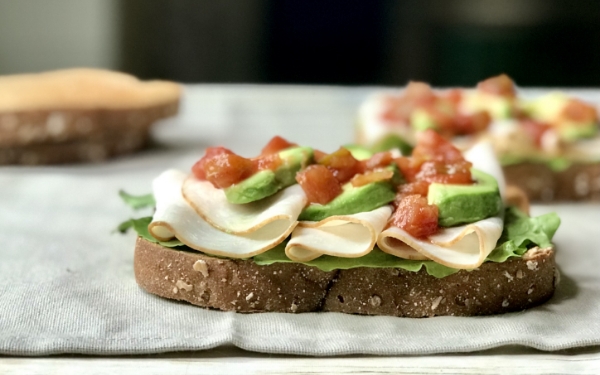 Slice of whole wheat toast topped with lettuce, sliced turkey and avocado slices